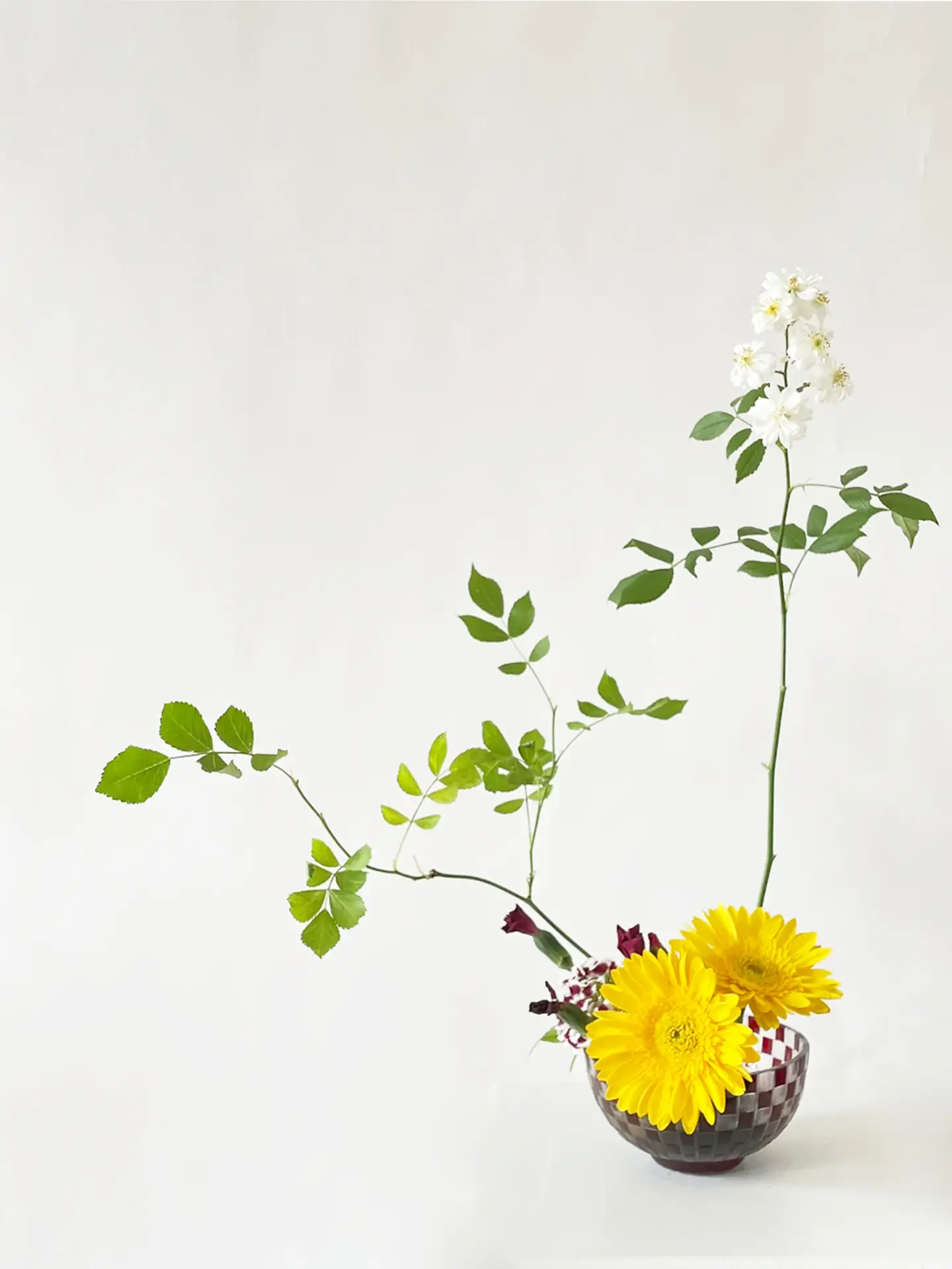 Japanese Ikebana arrangement with yellow gerbera, white roses, and green foliage in a traditional cut-glass Ichimatsu pattern Kiriko vase— floral art in Berlin by suminumi