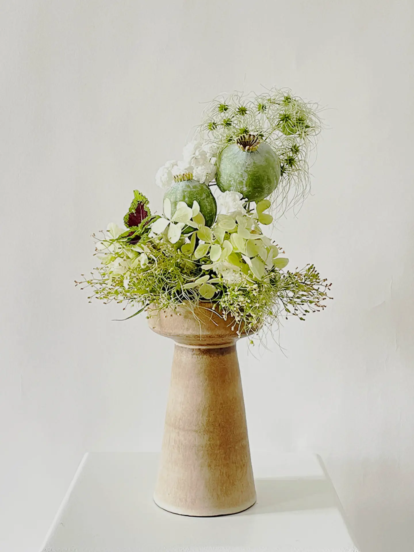 Wedding-inspired ikebana arrangement with hydrangeas, nigella, and poppy seedpods in a handcrafted pedestal vase by Verena De Hoog, created in Berlin by suminumi