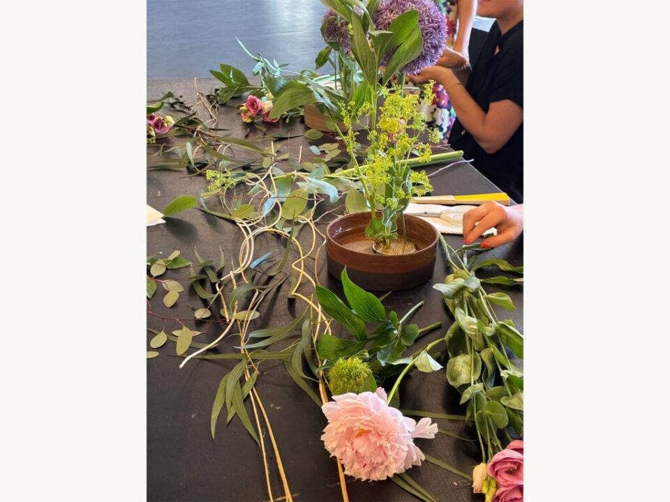 Close-up of a participant creating an Ikebana arrangement with seasonal flowers